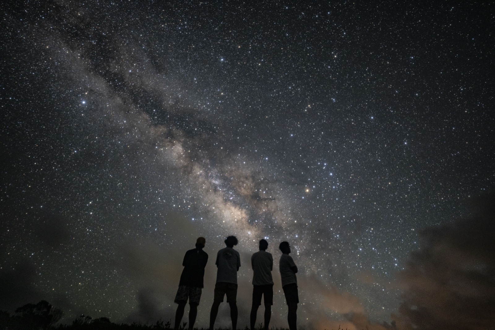 宮古島の星空ツアーで、4名のグループが天の川を見上げる様子